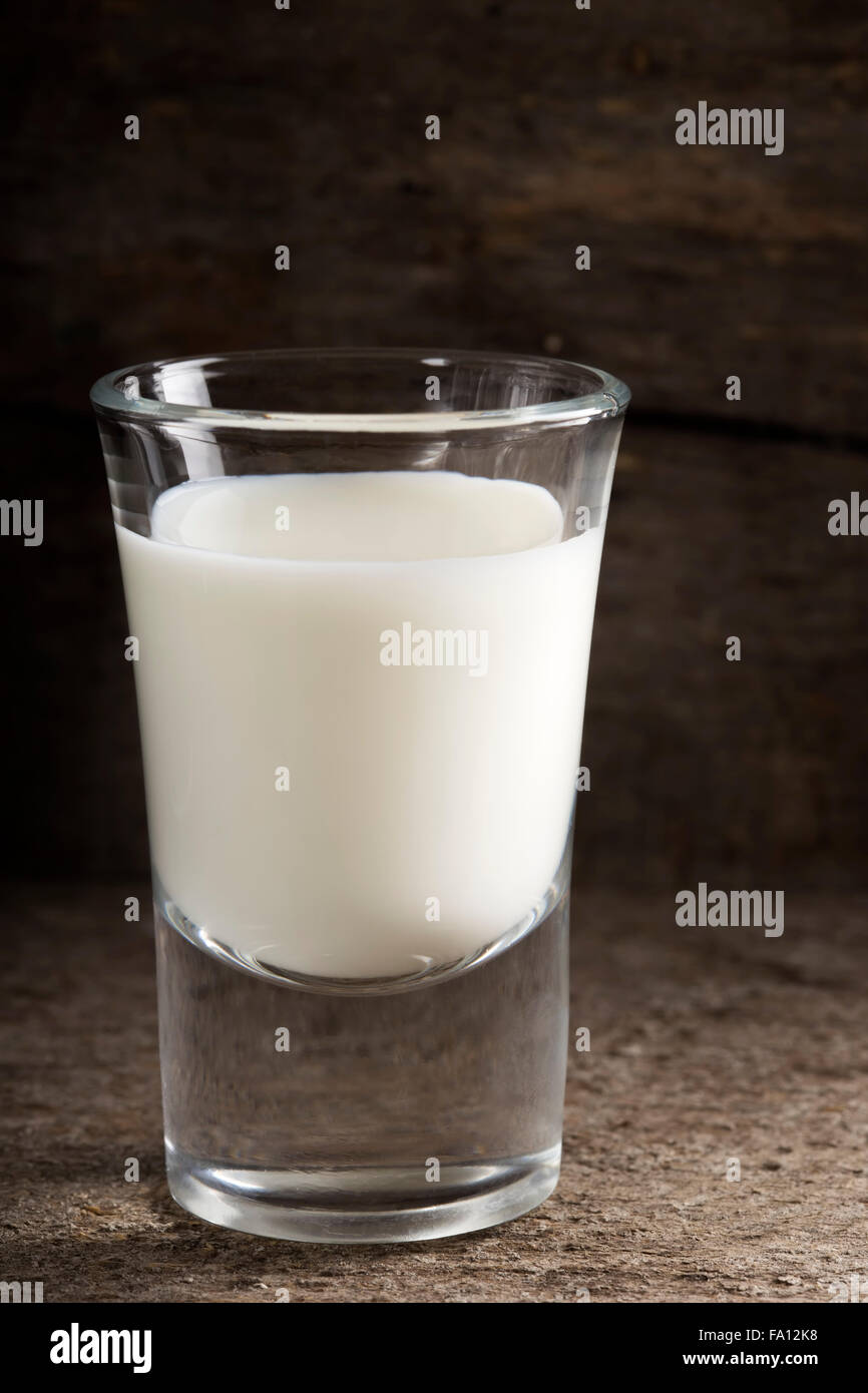 Shot of milk standing on old wooden table Stock Photo