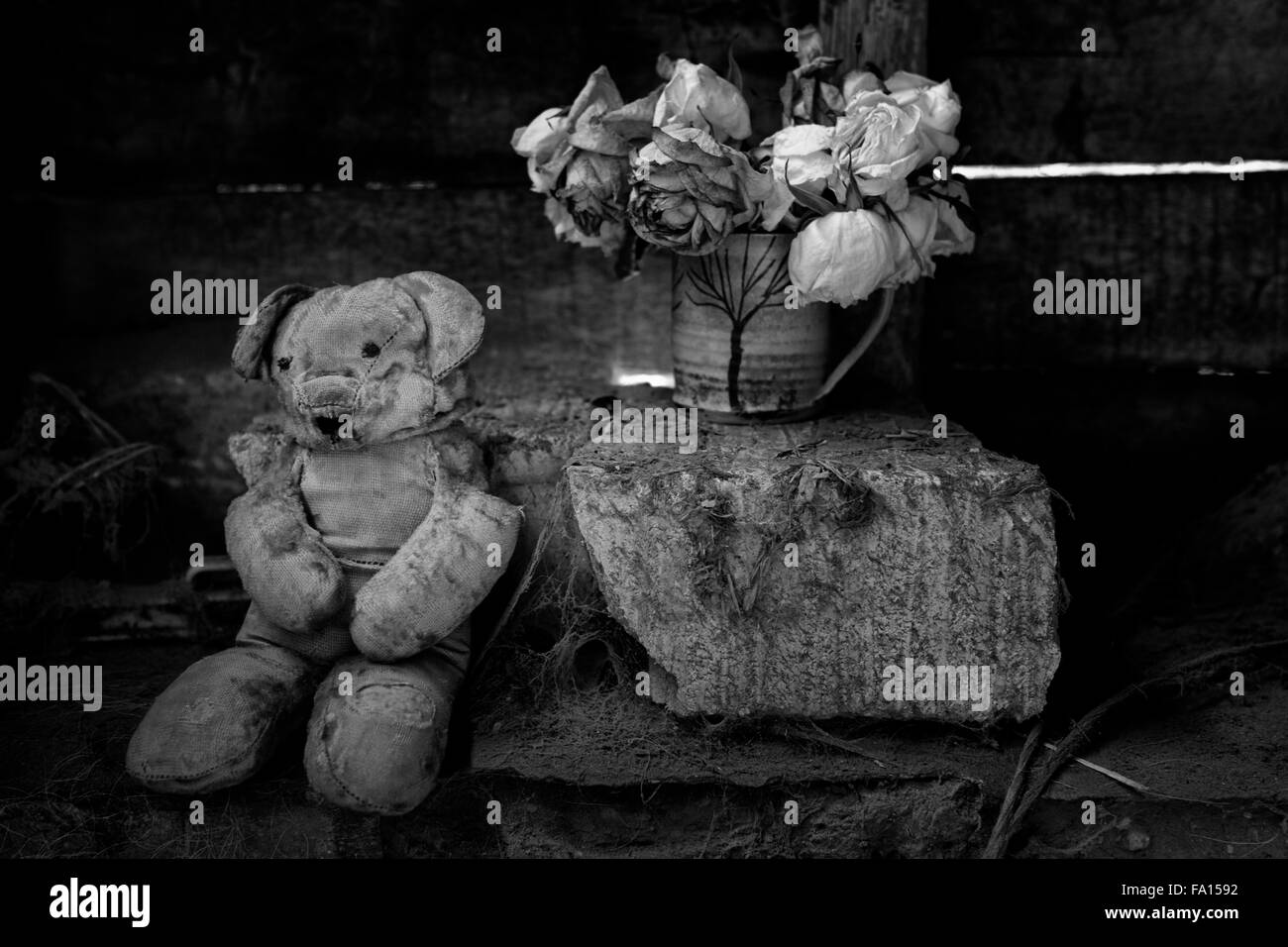 Vintage teddy bear with faded roses in a grungy setting Stock Photo