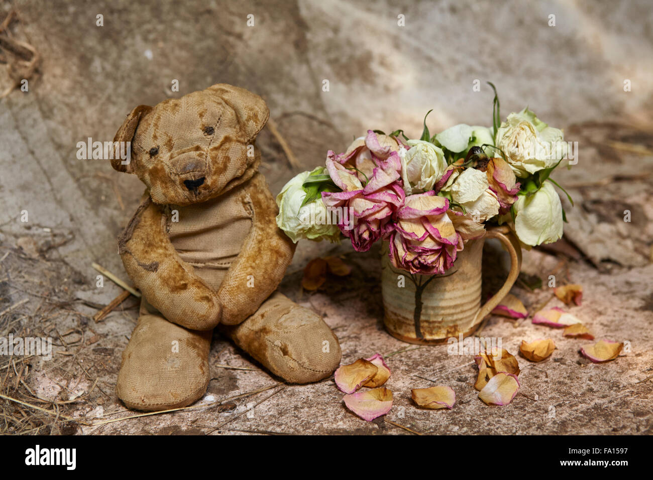Vintage teddy bear with faded roses in a grungy setting Stock Photo