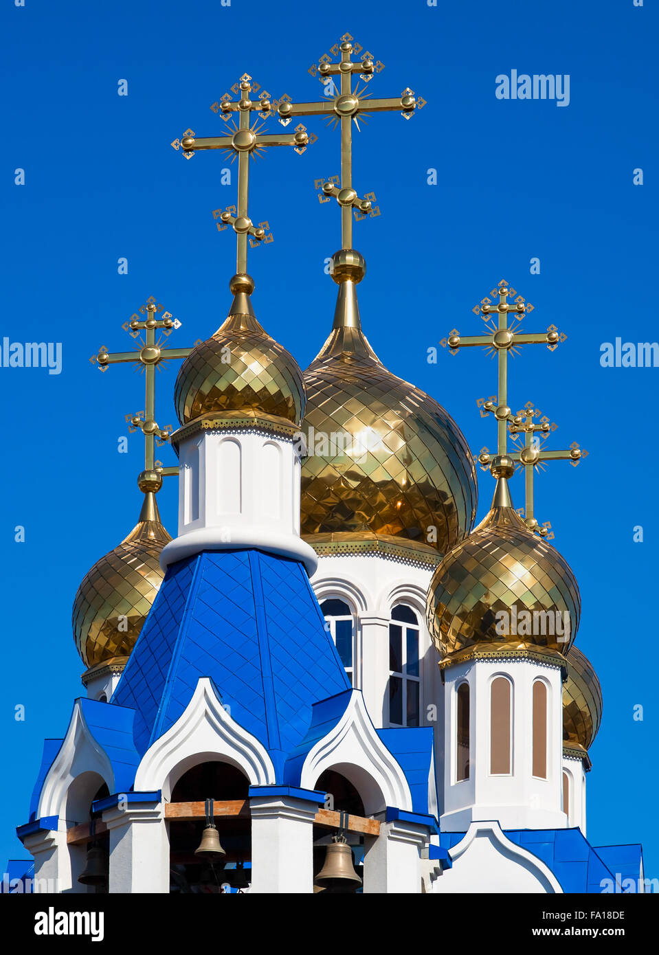Golden domes of Russian orthodox church with cross against blue sky ...