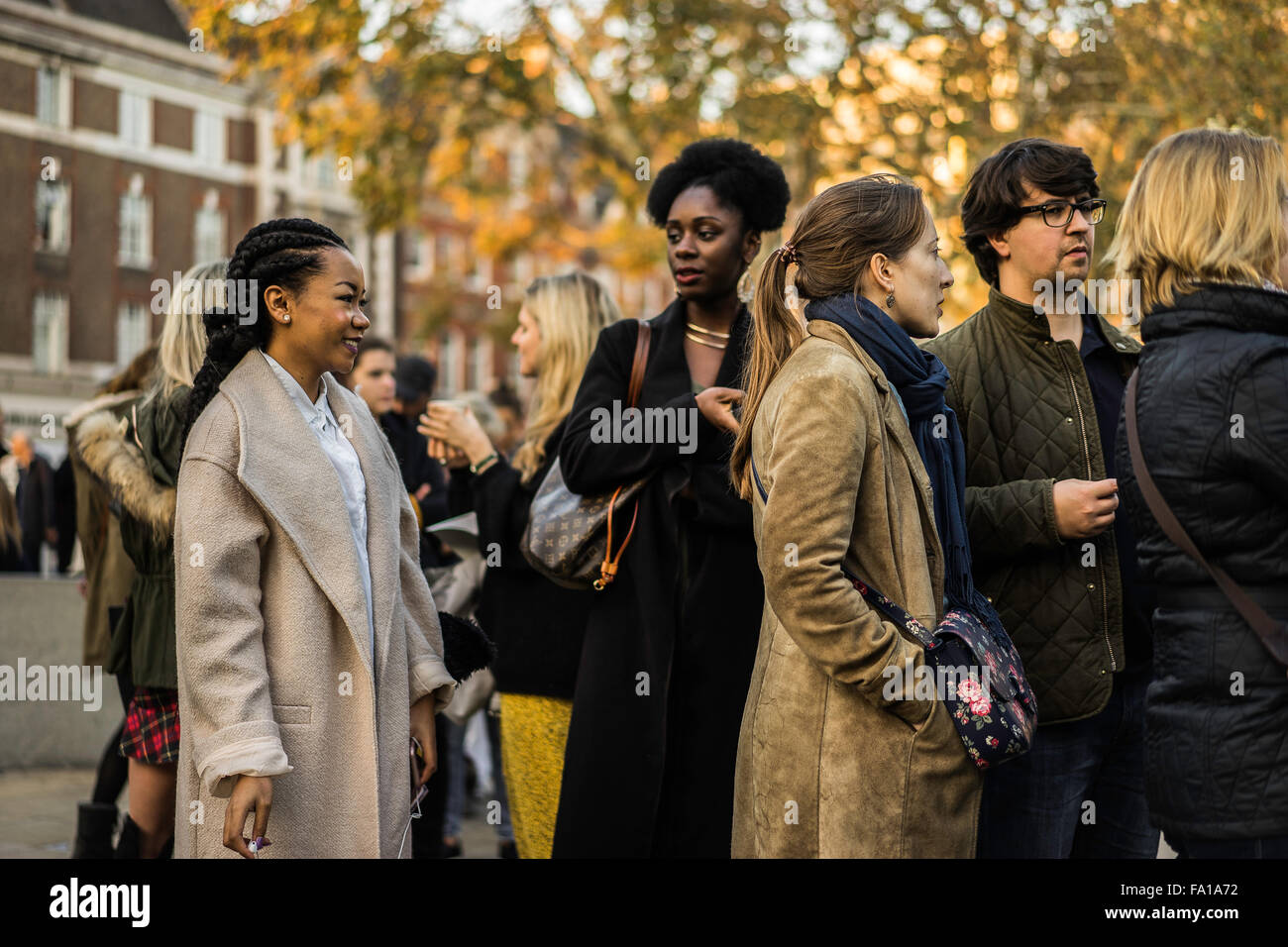 Trendy people chatting in a queue in central London Stock Photo