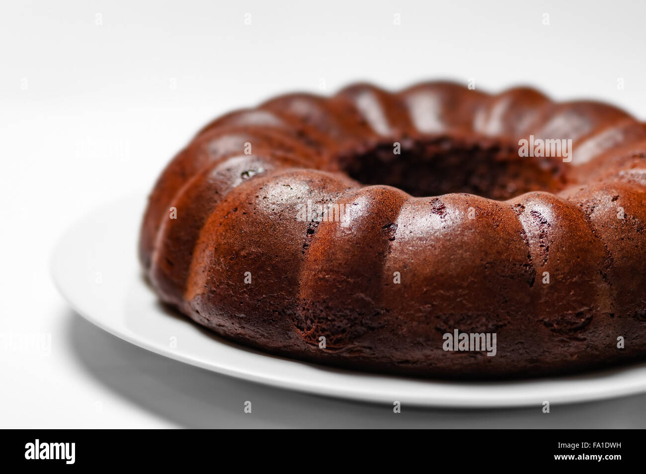 Chocolate bunt cake whole sponge on a plate white background closeup Stock Photo