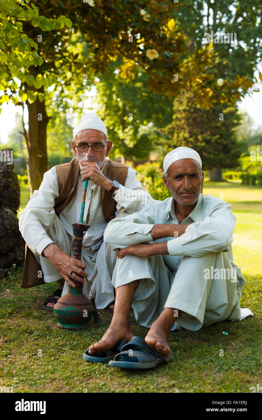 Two senior Kashmiri muslim men wearing white hats sitting in the