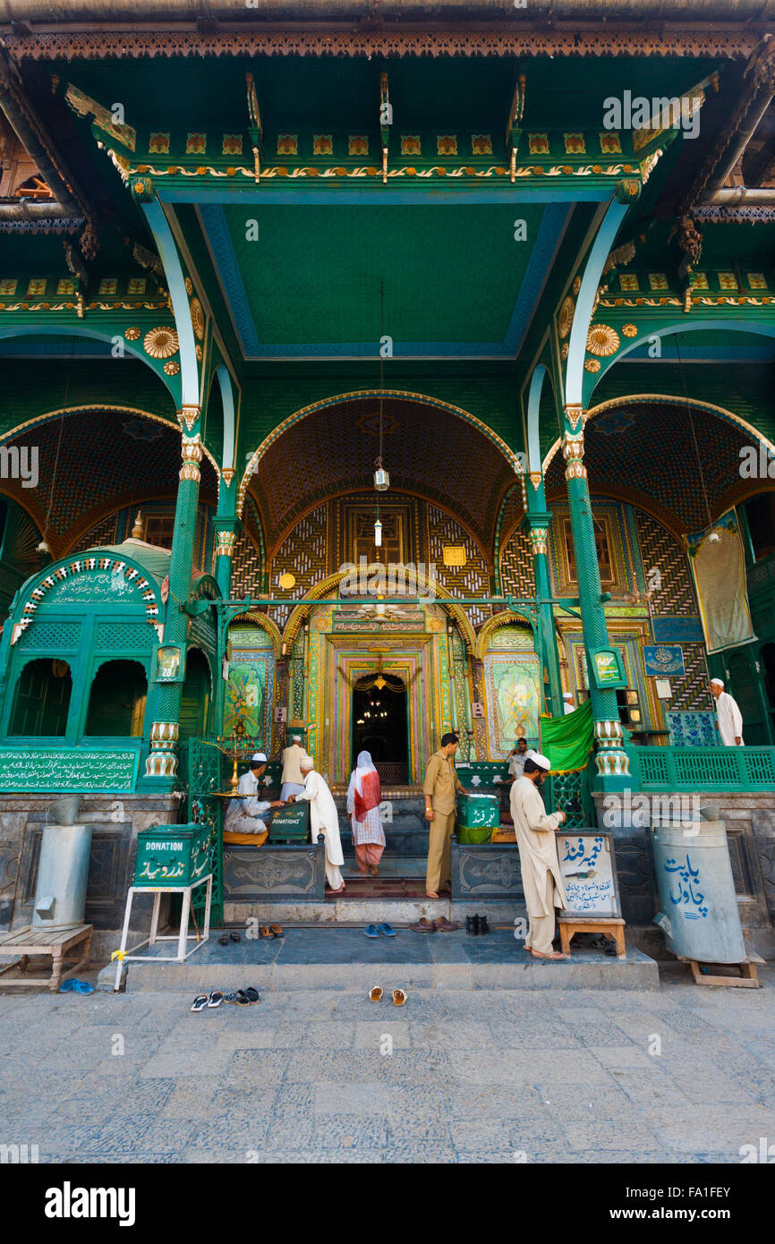 Muslim people enter the front entrance to a green uniquely wooden mosque, Shah E Hamdan for evening prayers in Kashmir Stock Photo