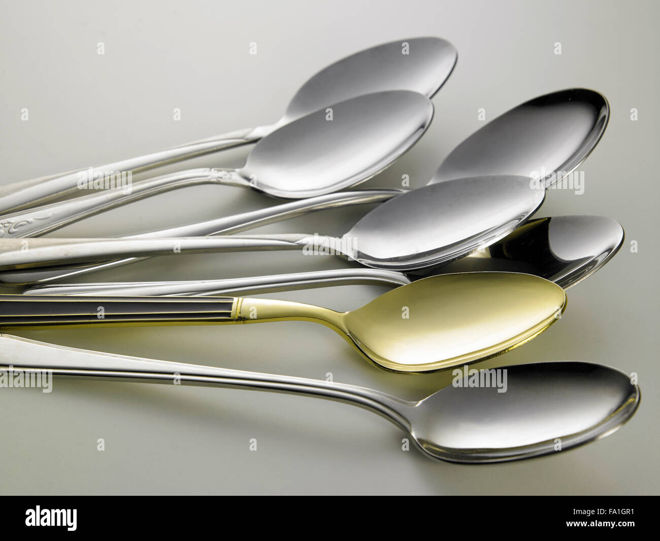 golden spoon stand out from other spoons Stock Photo
