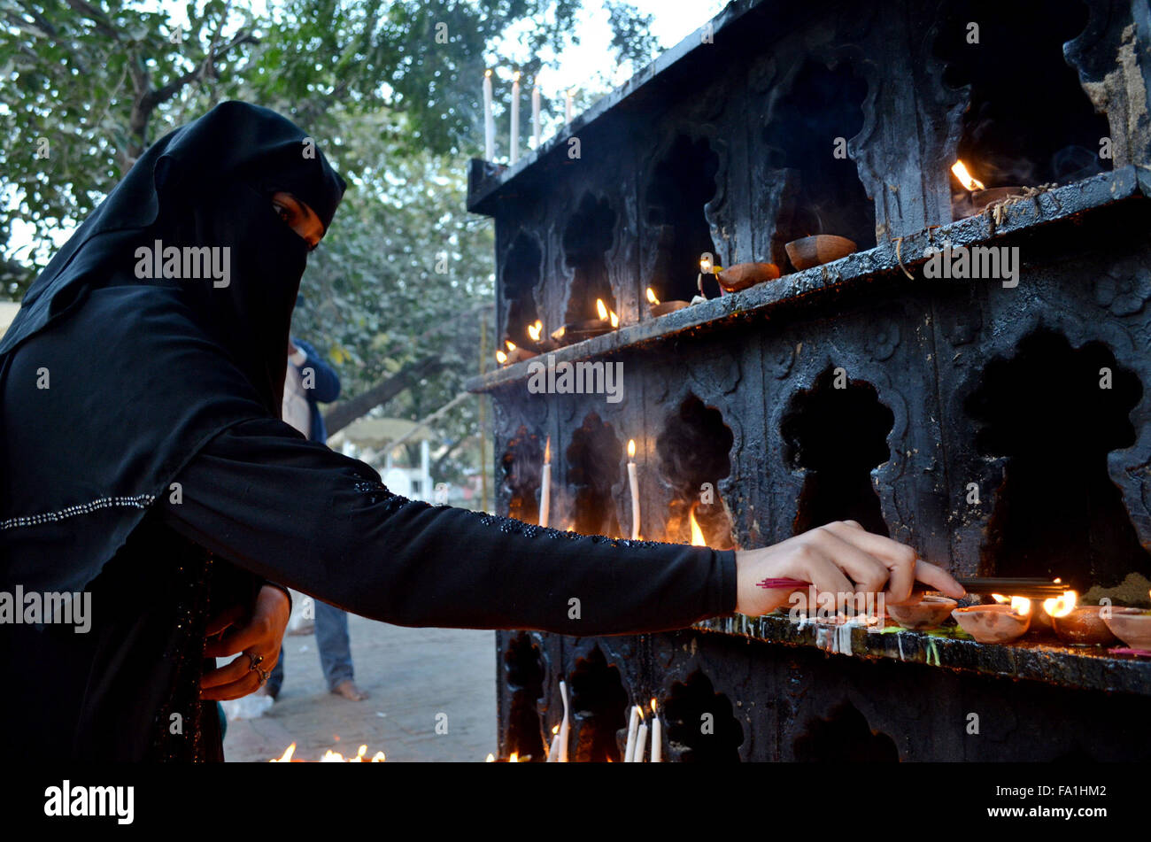 Lahore. 19th Dec, 2015. A Muslim devotee lights candles and oil lamps at the shrine of the Sufi saint Mian Mir Sahib during a festival to mark the saint's death anniversary in eastern Pakistan's Lahore, Dec. 19, 2015. Hundreds of devotees are attending the two-day festival. © Jamil Ahmed/Xinhua/Alamy Live News Stock Photo