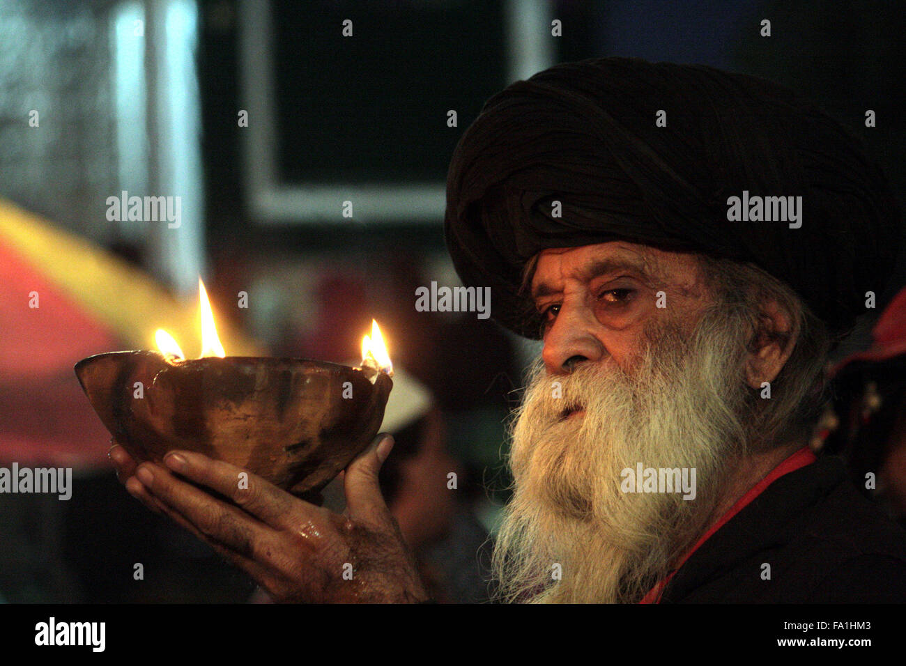 Lahore. 19th Dec, 2015. A Muslim devotee holds an oil lamp at the shrine of the Sufi saint Mian Mir Sahib during a festival to mark the saint's death anniversary in eastern Pakistan's Lahore, Dec. 19, 2015. Hundreds of devotees are attending the two-day festival. © Jamil Ahmed/Xinhua/Alamy Live News Stock Photo