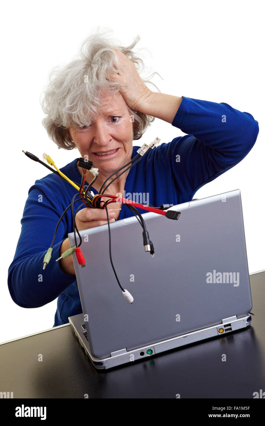 Frustrated old woman with laptop and many different computer cables Stock Photo