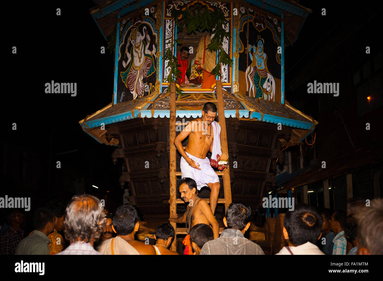 Brahmin priest exiting the stairs of the small ratha chariot among a crowd of hindus during a monthly full moon hindu festival Stock Photo