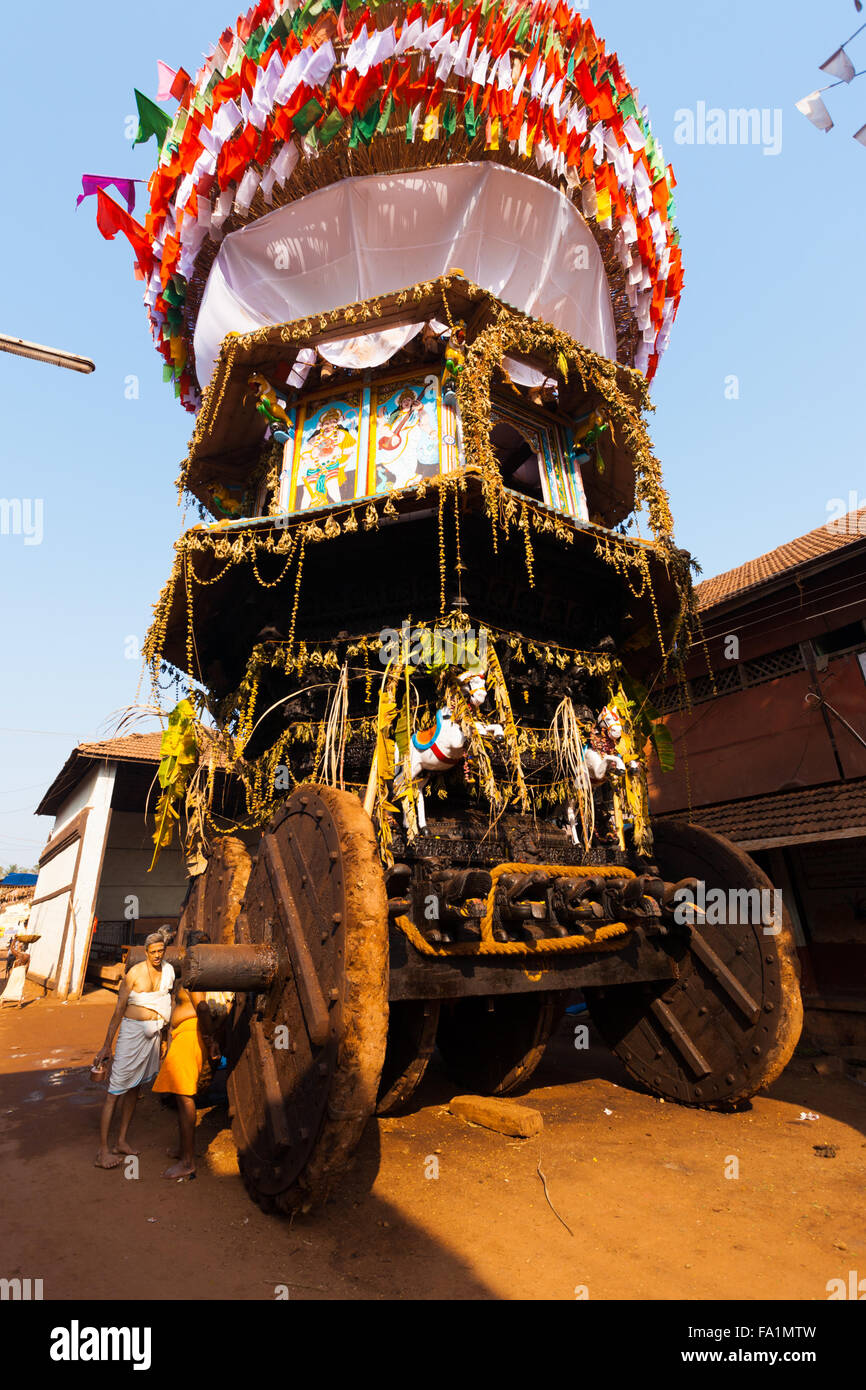 Two brahmin priests standing next to large wheels of the big ratha chariot, a car used in Gokarna for Shivaratri festival Stock Photo