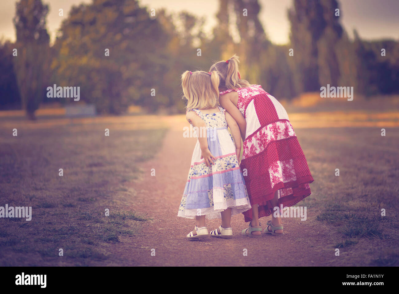 Two curious sisters looking at something in the outdoors Stock Photo