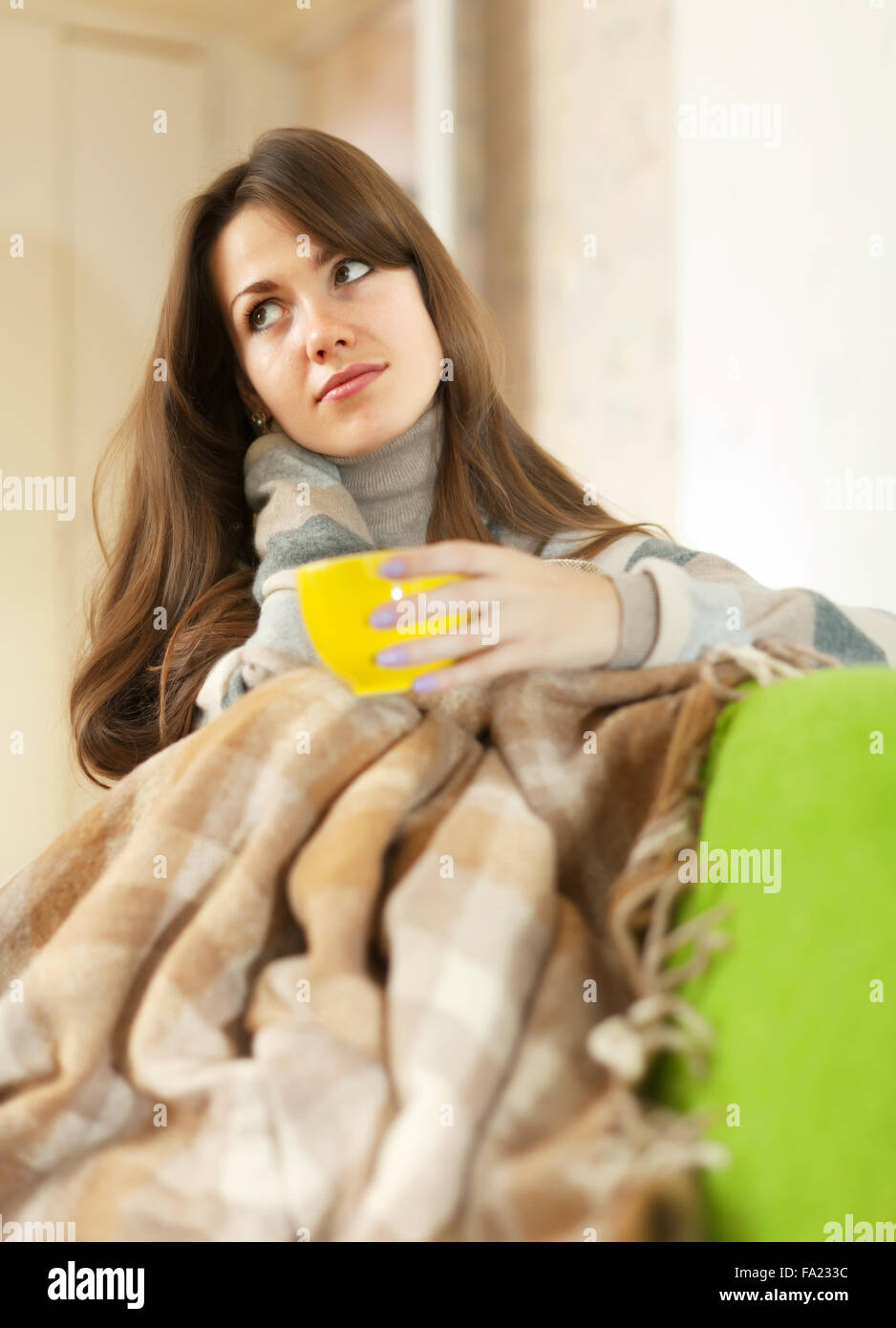 Girl sitting on sofa in livingroom with cup of tea Stock Photo - Alamy