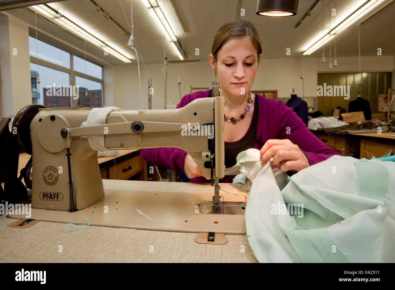Custom tailor works at a sewing machine. Stock Photo