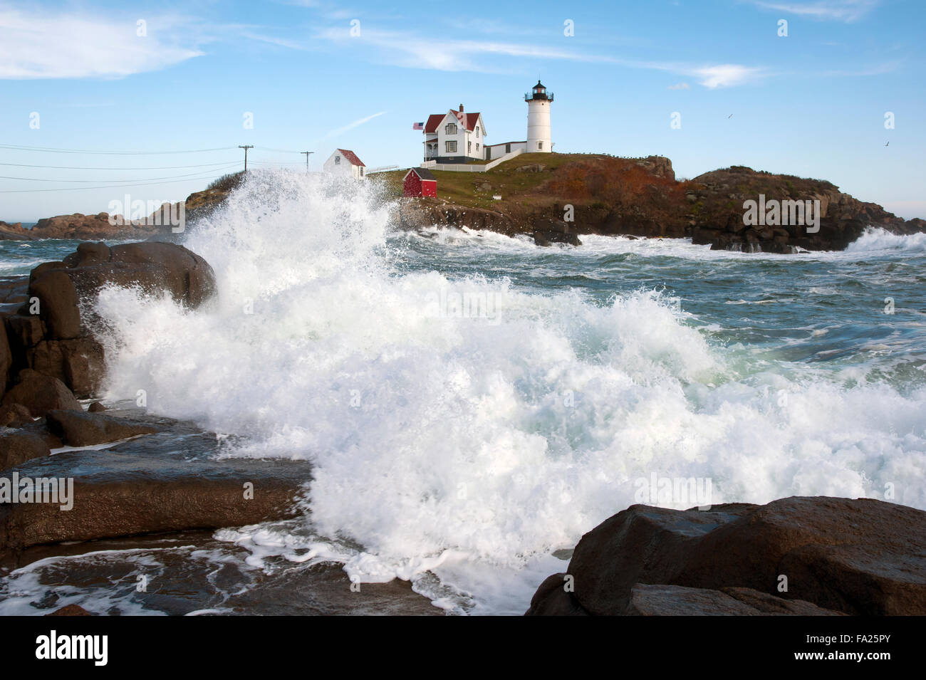 Waves crashing along the rocky shoreline near Nubble lighthouse in Maine at high tide. It is one of the most photographed attractions on the seacoast. Stock Photo