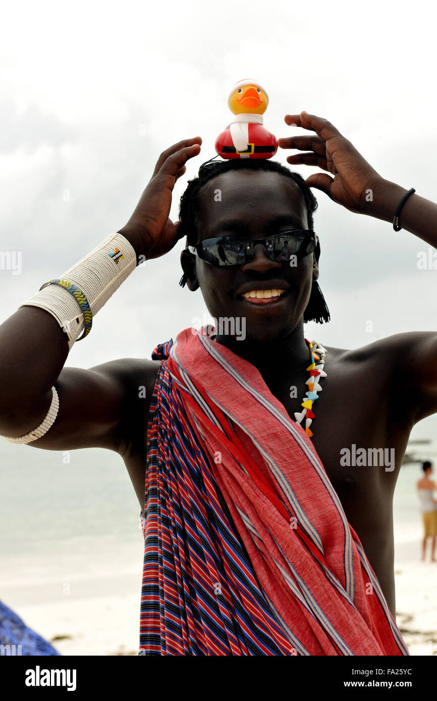 A Masai tribesman on a beach playfully sports a Christmas duck on his head in Jambiani, Zanzibar, Tanzania, East Africa Stock Photo