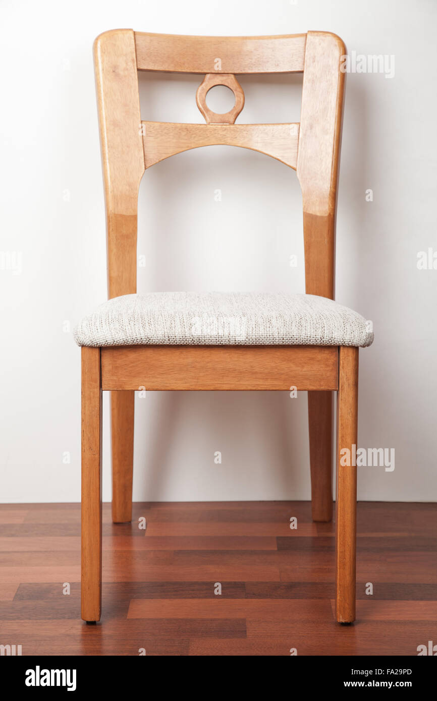 Wooden chair against a white wall, closeup vertical photo Stock Photo