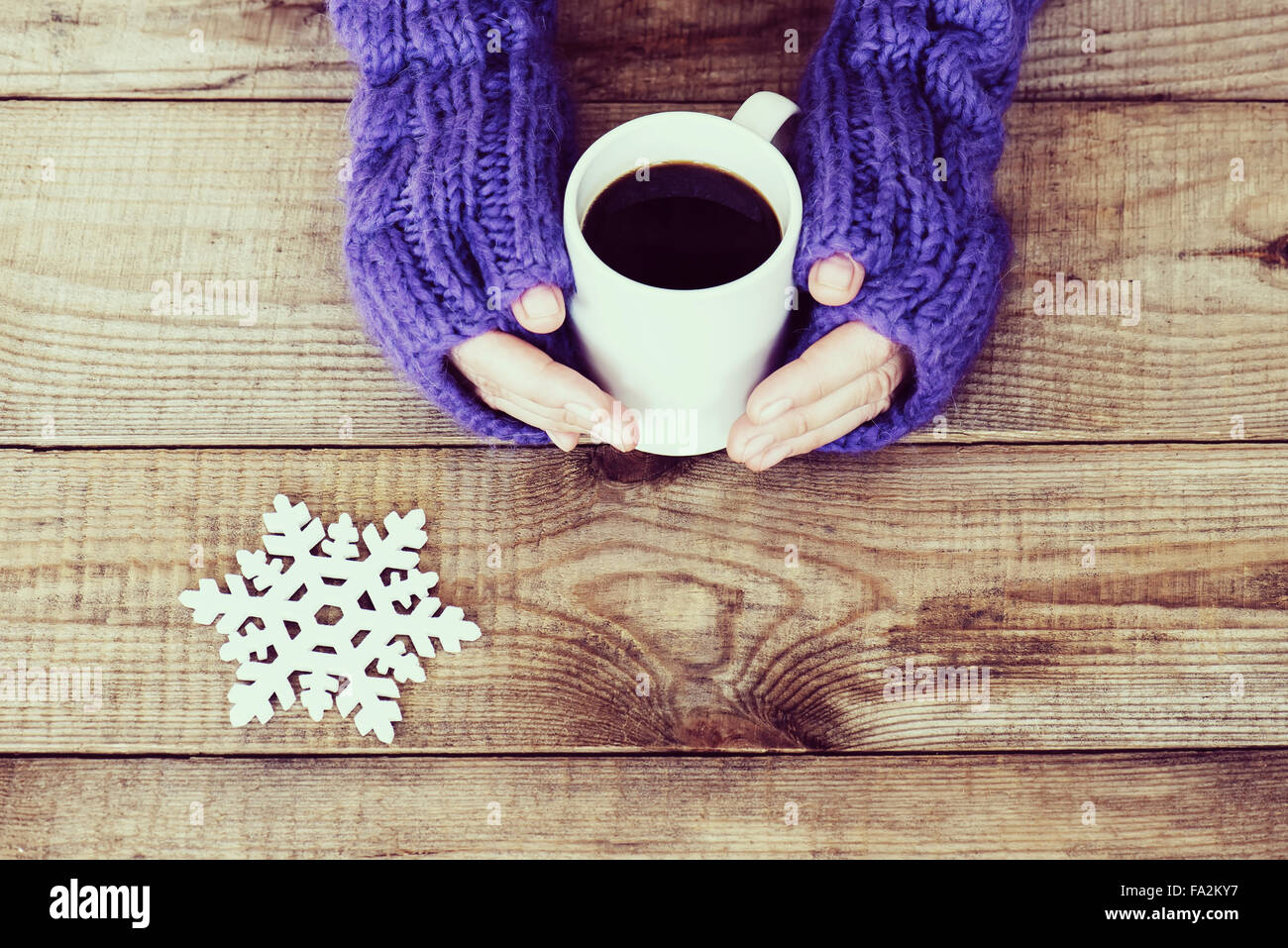 Woman hands in teal gloves are holding a mug with hot coffee or cocoa ...
