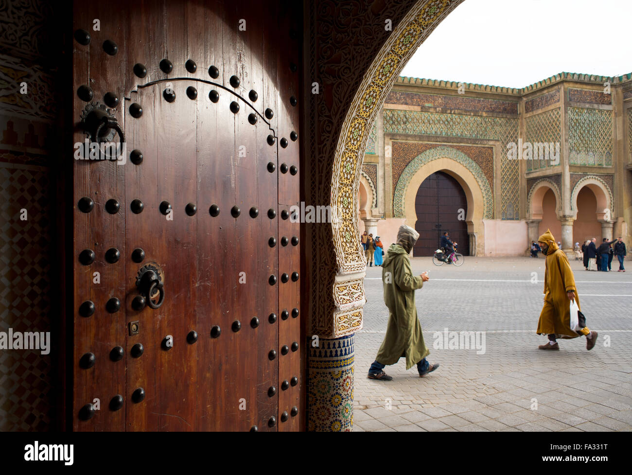 People with djellaba walking in front of The Bab el Mansour gate, view from inside a entry hall of a classical building. Meknes. Stock Photo