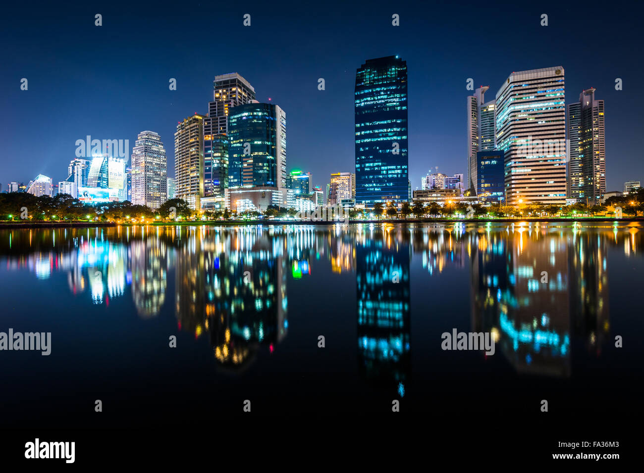 Modern skyscrapers and Lake Rajada at night, at Benjakiti Park, in Bangkok, Thailand. Stock Photo