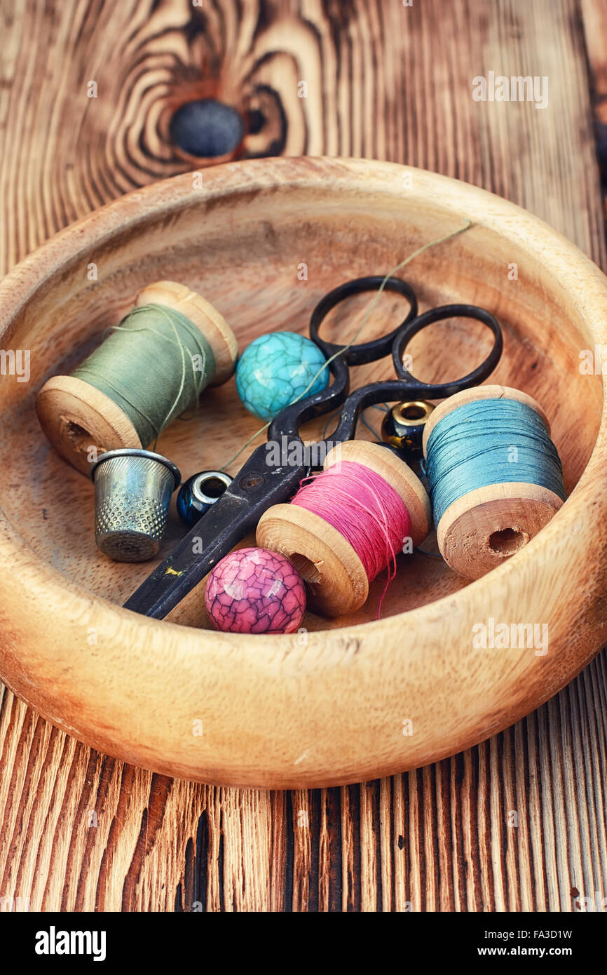 Scissors,buttons and thread in wooden bowl on background of pine Stock ...