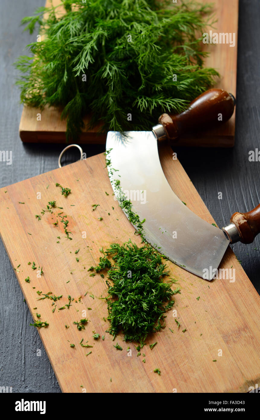 Chopping fresh dill with a curved mezzaluna knife Stock Photo