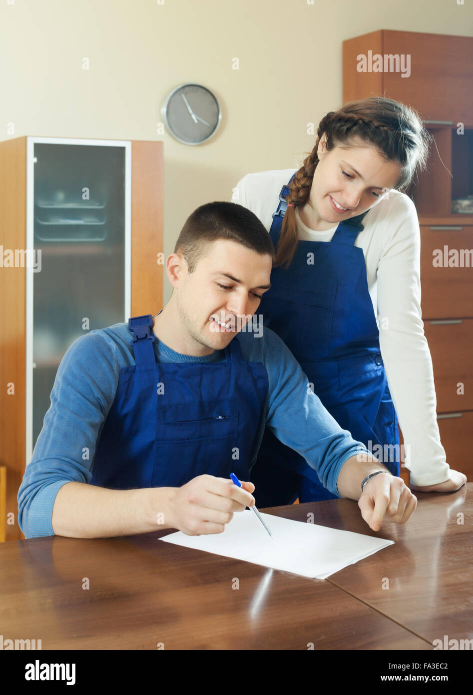 Teamwork of workers in uniform writing in questionnaire at table Stock
