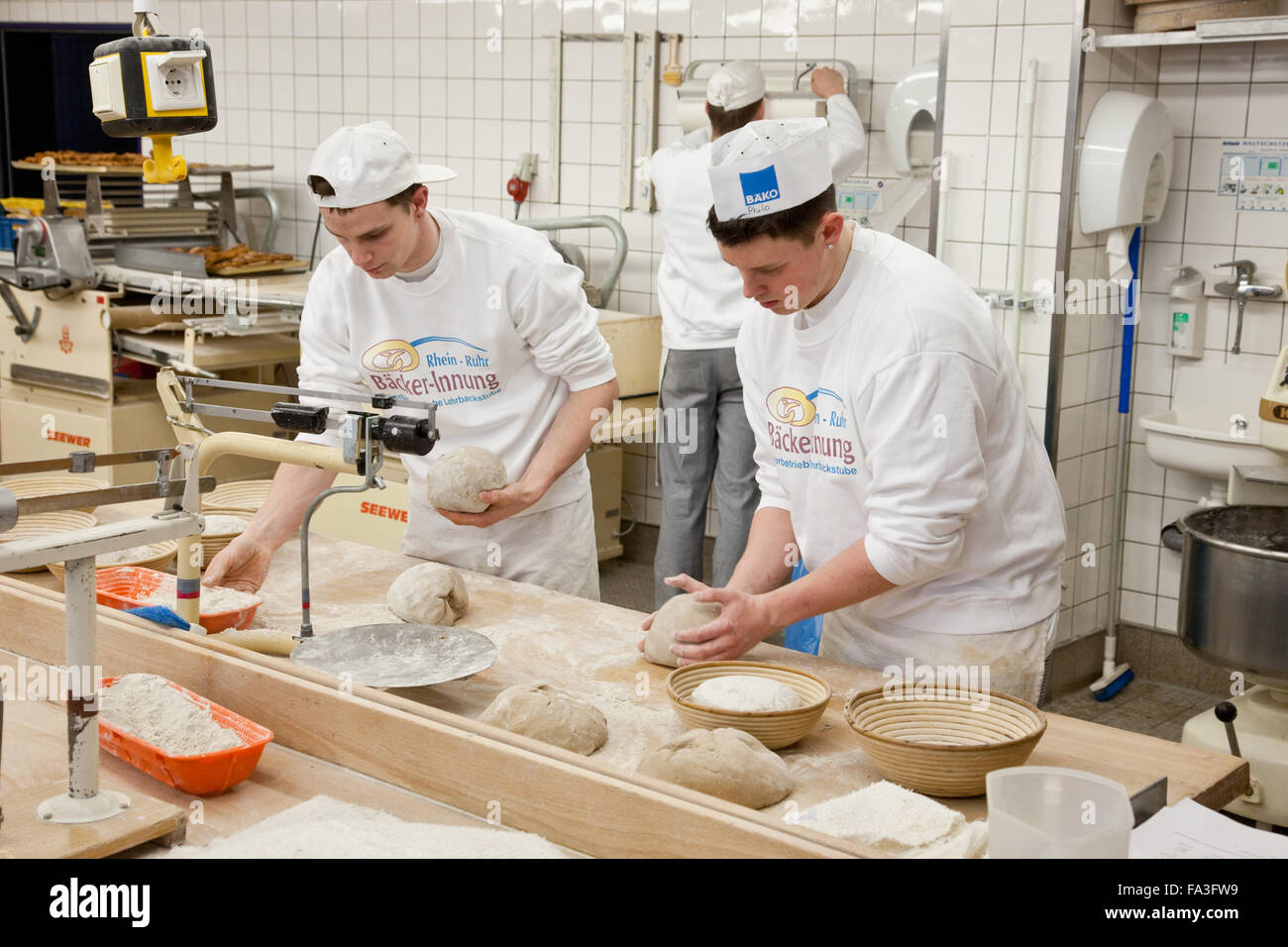 Baker apprentice kneads bread dough. Stock Photo