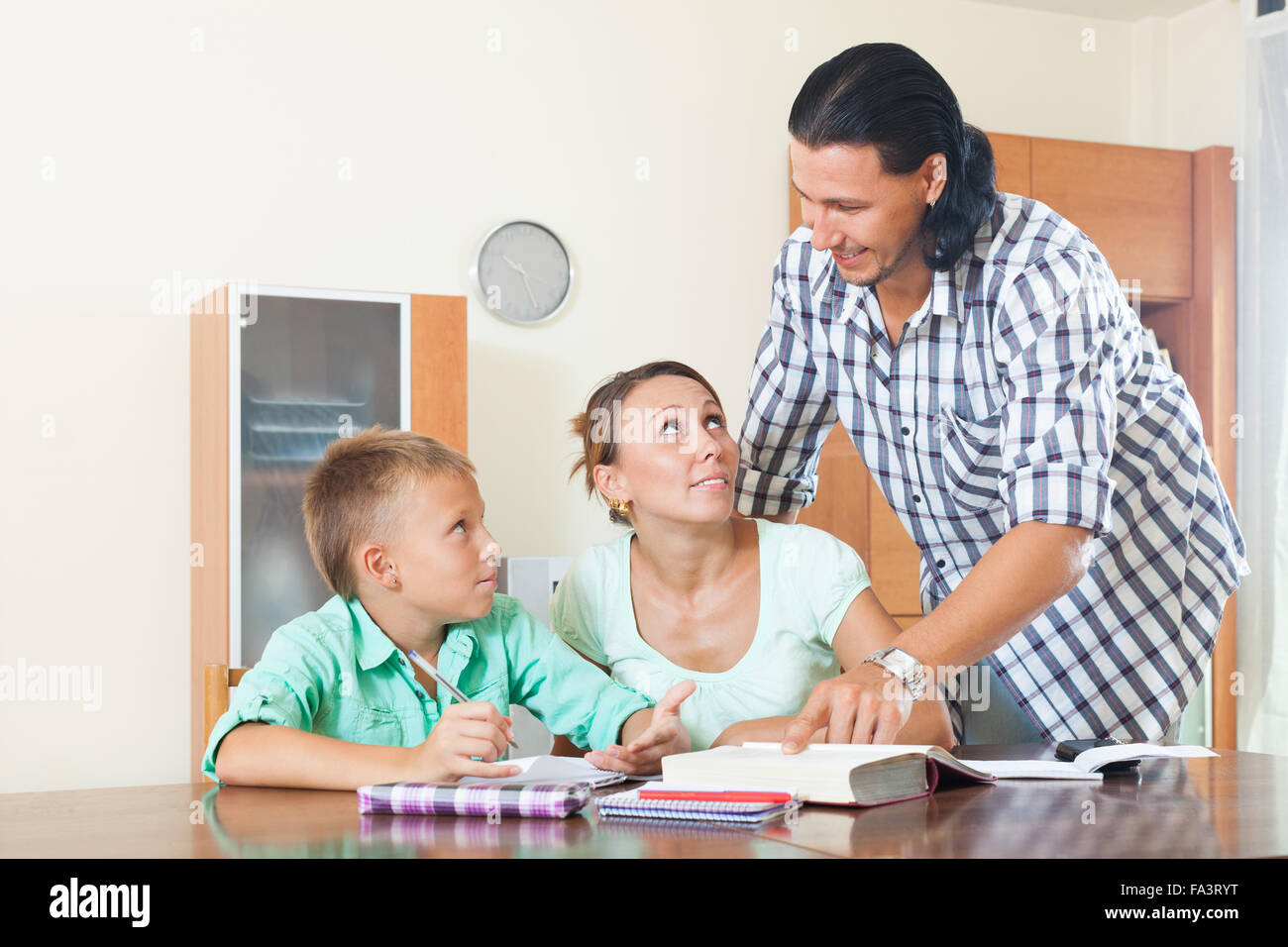Serious couple with a clever teenager schoolboy doing homework at home interior Stock Photo