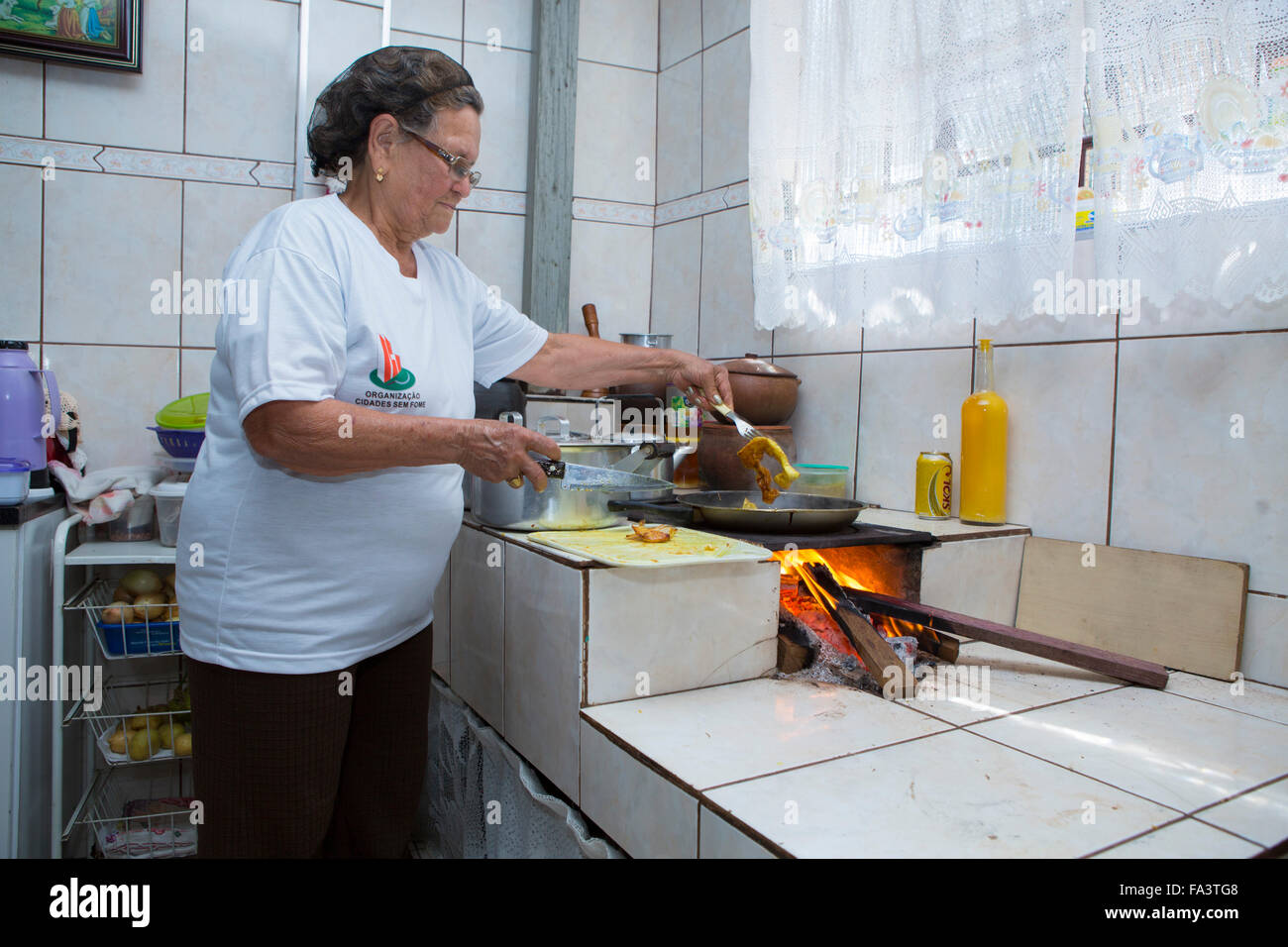 South America, Brazil, Sao Paulo. A local woman cooking food in her kitchen on a wood-fired traditional forno a lenha stove Stock Photo