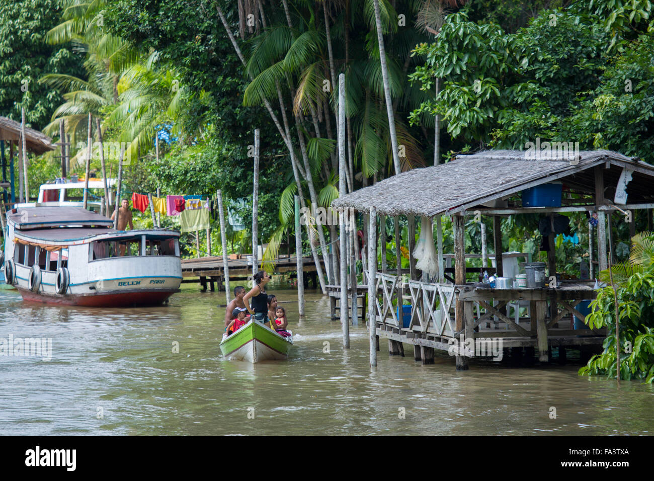 A traditional boat and river house on a creek in the Brazilian Amazon Stock Photo