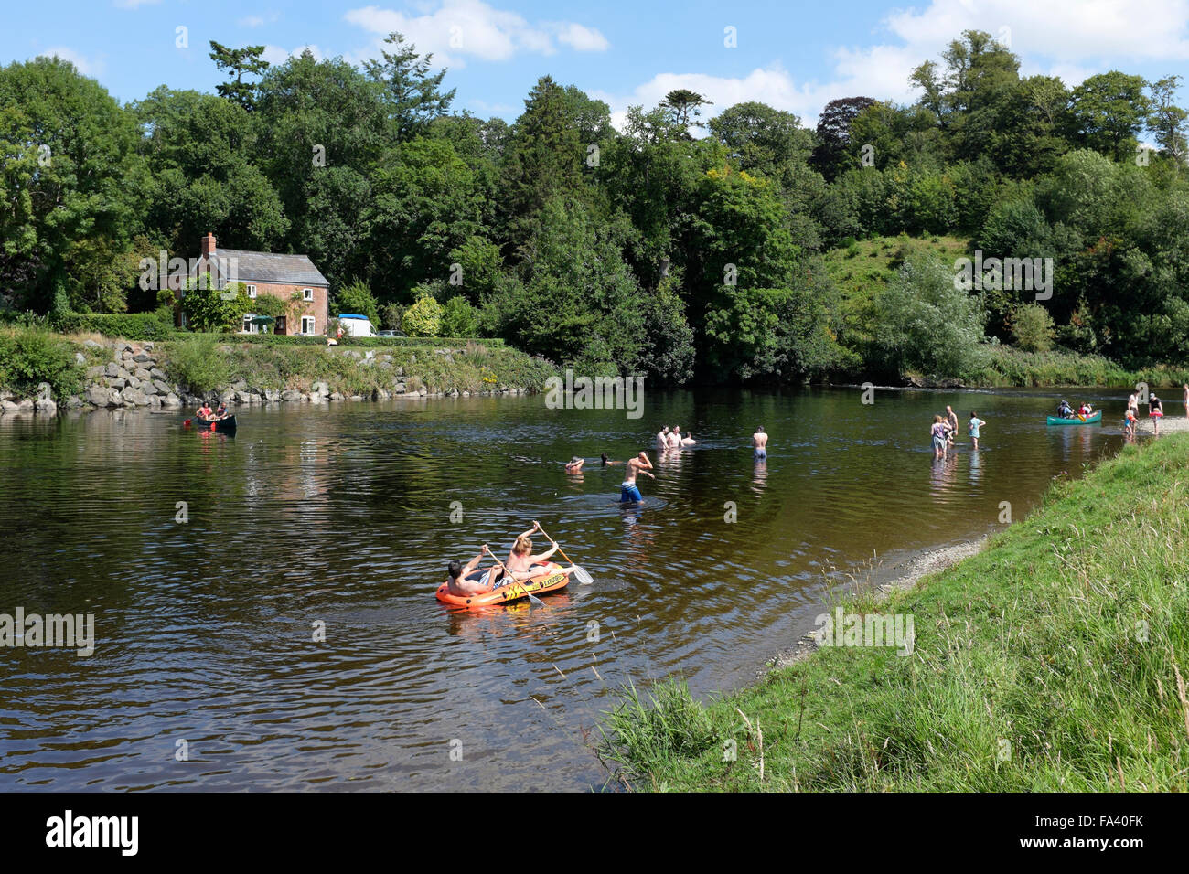 People enjoying boating, paddling and swimming on and in the river Wye on the outskirts of the book town Hay-on-Wye, Powys, Wale Stock Photo