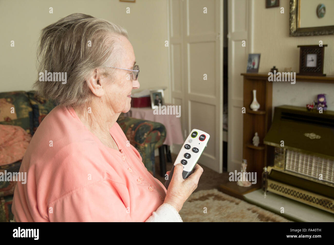 90 year old lady using large button TV remote control. Stock Photo
