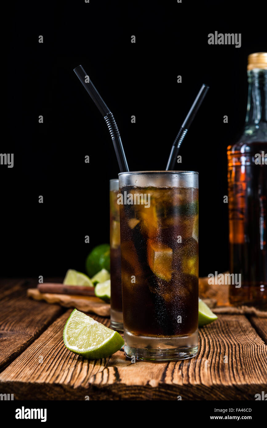 Cold Longdrink (Cuba Libre) with brown rum and fresh lime on rustic wooden background Stock Photo