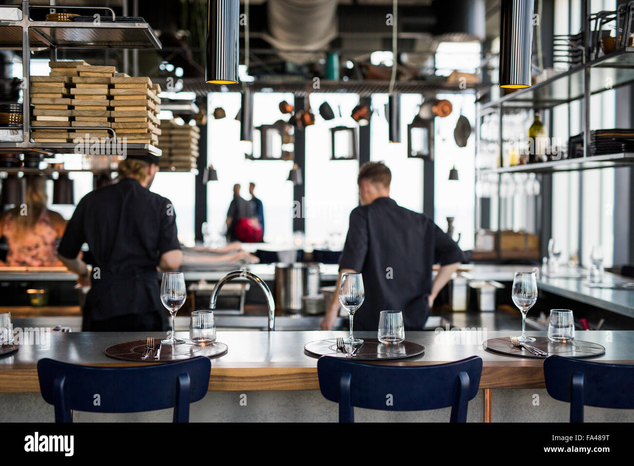 Rear view of chefs cooking food in kitchen at Skybar restaurant Stock