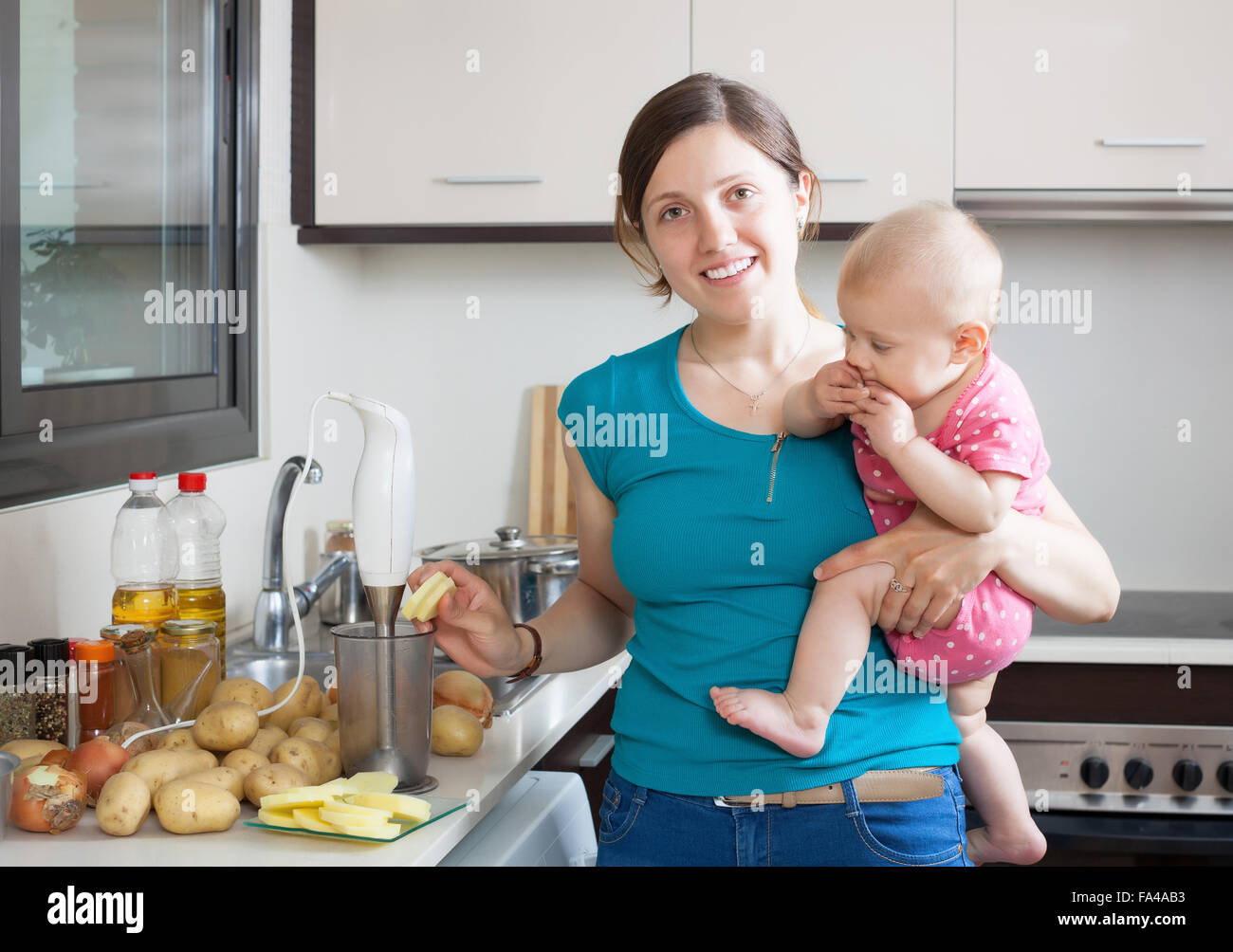 Happy mother with child cooking mashed potatoes in kitchen at home Stock Photo