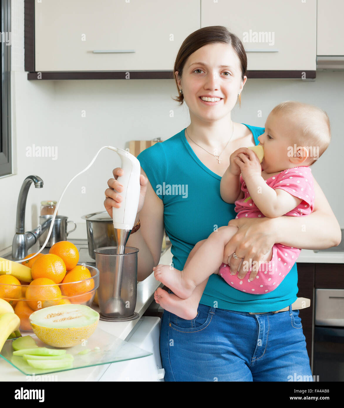 Happy woman with baby together cooking fruit puree  in kitchen at home Stock Photo