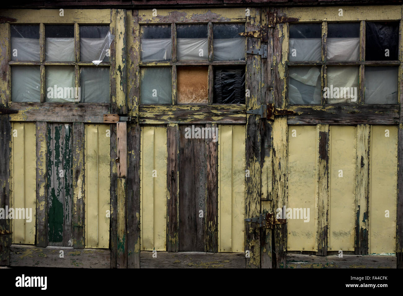 Three light green or yellow, weathered, worn doors with broken windows and peeling paint. Stock Photo