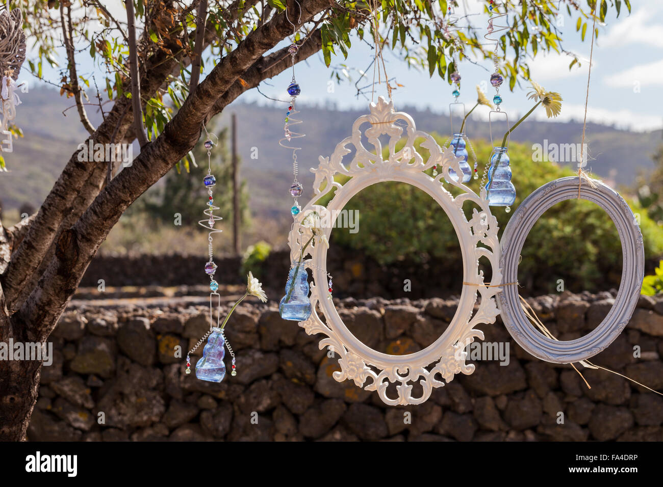 Picture frames and other baubles and flowers hanging in a tree as decorations for an outdoor celebration such as a wedding party Stock Photo