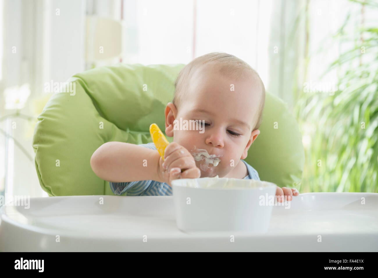 Cute little baby boy eating food on high chair, Munich, Bavaria, Germany Stock Photo
