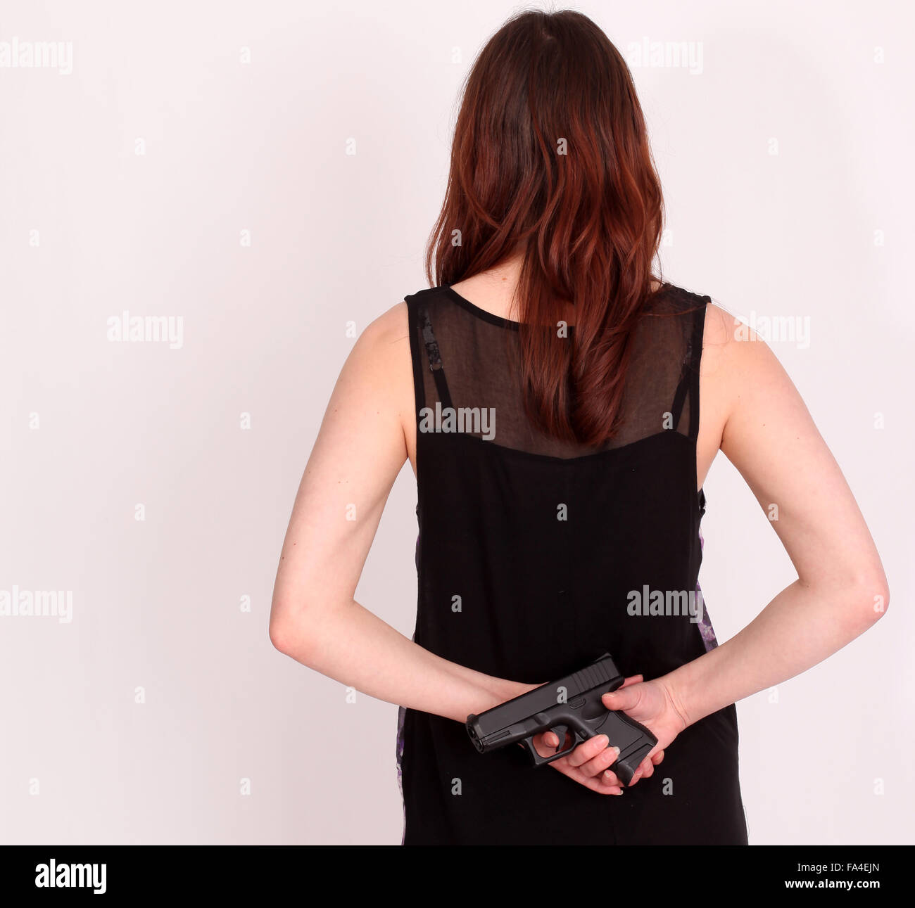 Young woman with a gun behind her back Stock Photo