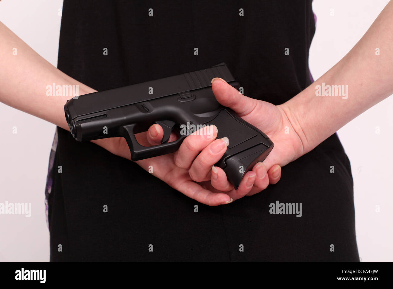 Young woman with a gun behind her back Stock Photo