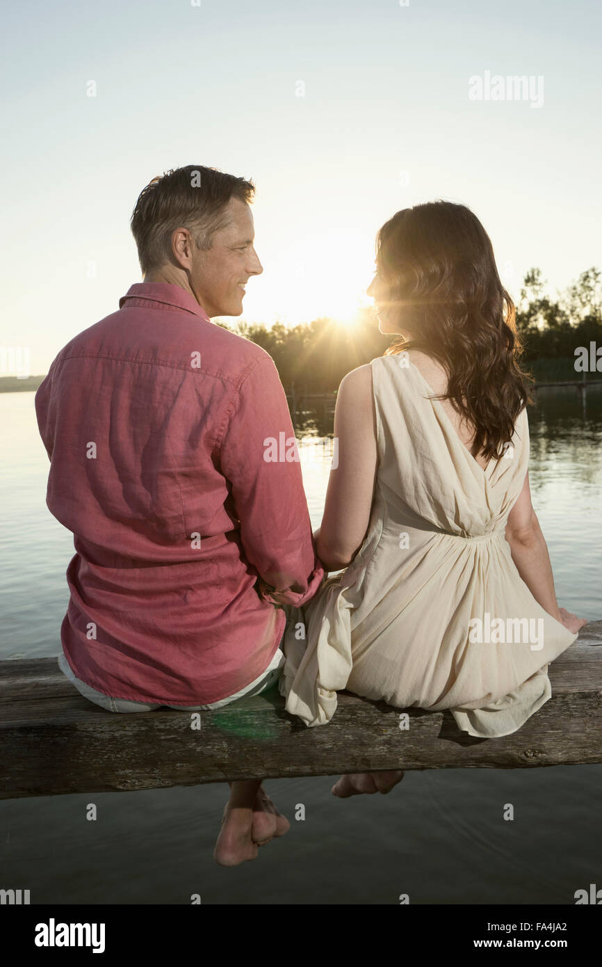 Mature couple looking at each other on pier at sunset, Bavaria, Germany Stock Photo