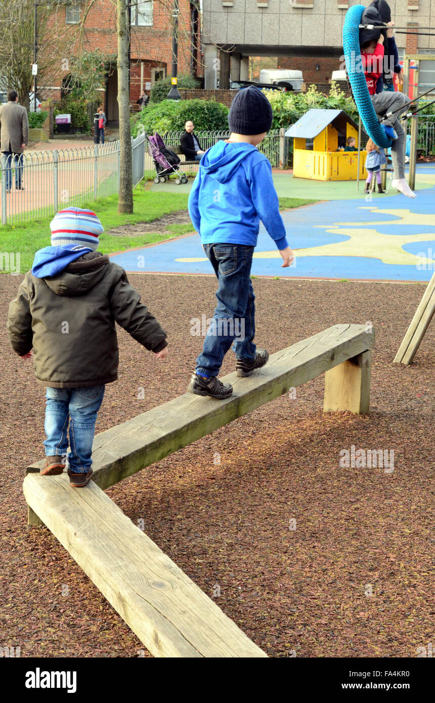 Children playing on a balance beam in a playground in Windsor. Stock Photo