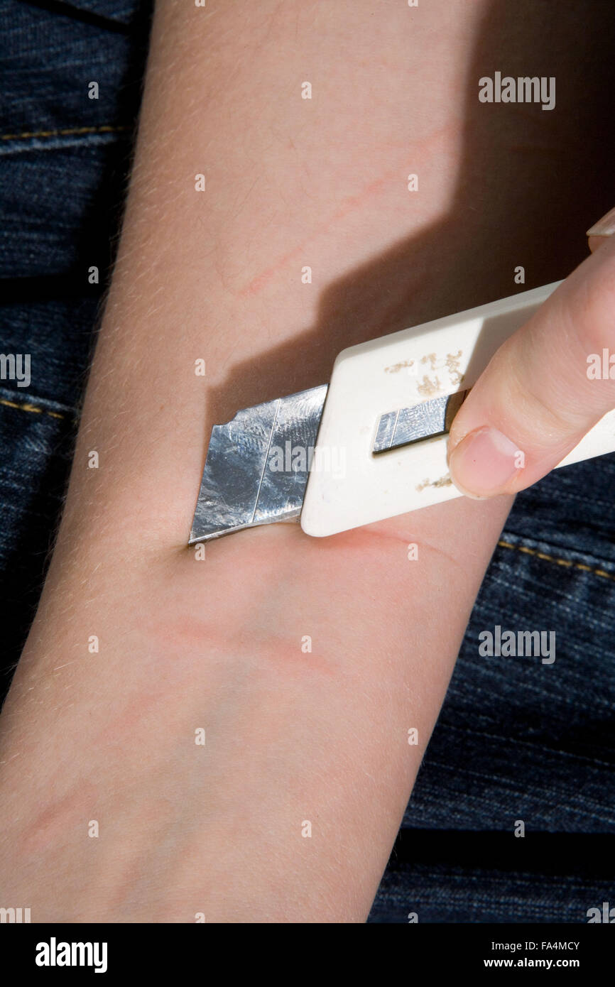 Young woman inflicting selfharm to her wrist Stock Photo - Alamy