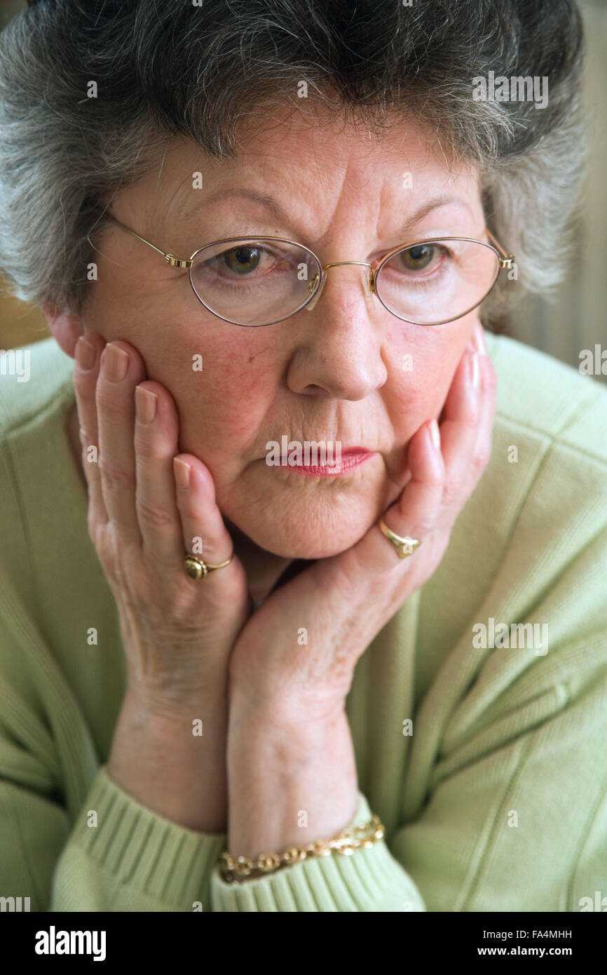 Woman; looking serious; resting her chin on her hands, Stock Photo
