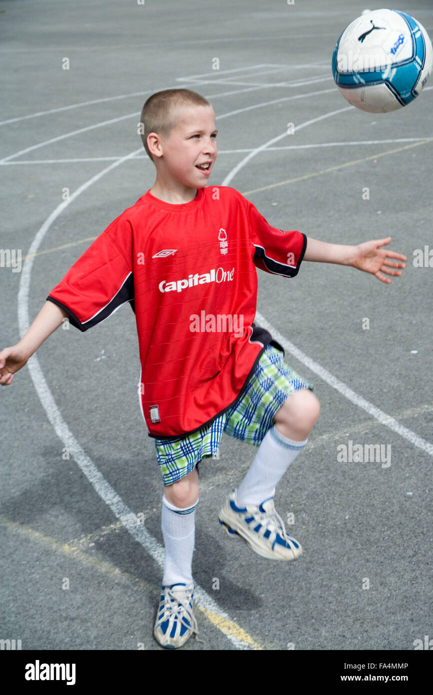 Young boy playing with football in school playground, Stock Photo