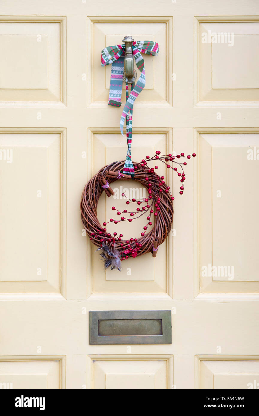 Christmas wicker and red berry wreath on a white wooden door Stock Photo