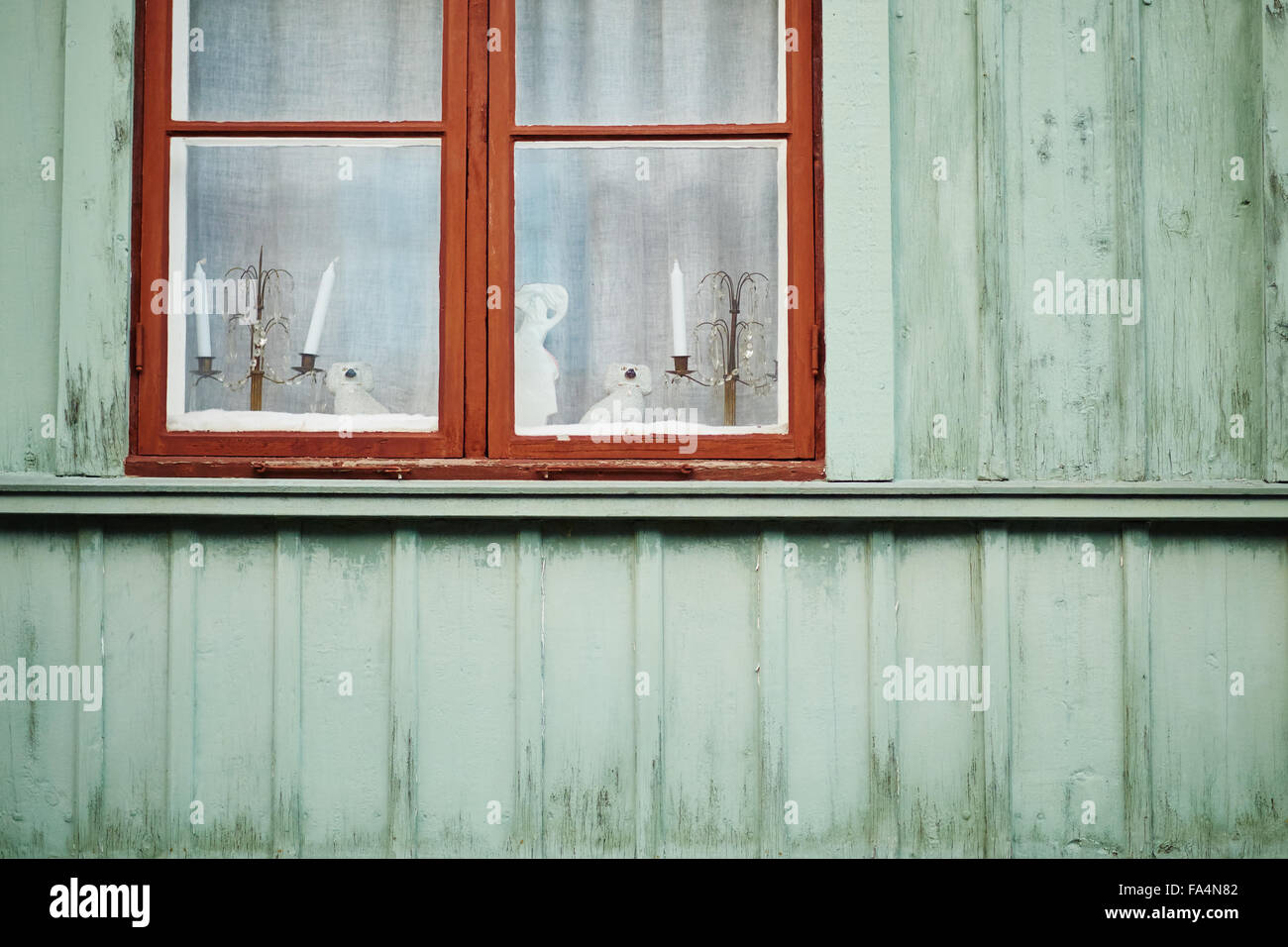 Christmas decorations and candles in window of traditional wooden house