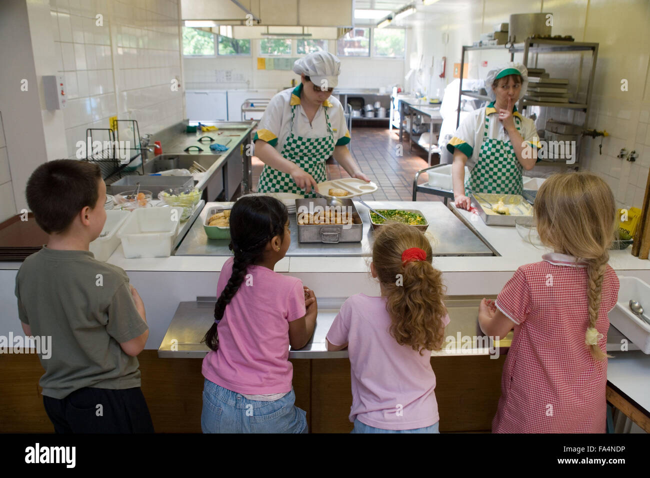 Children standing at counter in school canteen waiting for food Stock