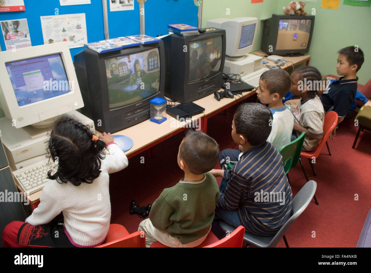 Group of primary school children using computers and watching televisions in classroom, Stock Photo